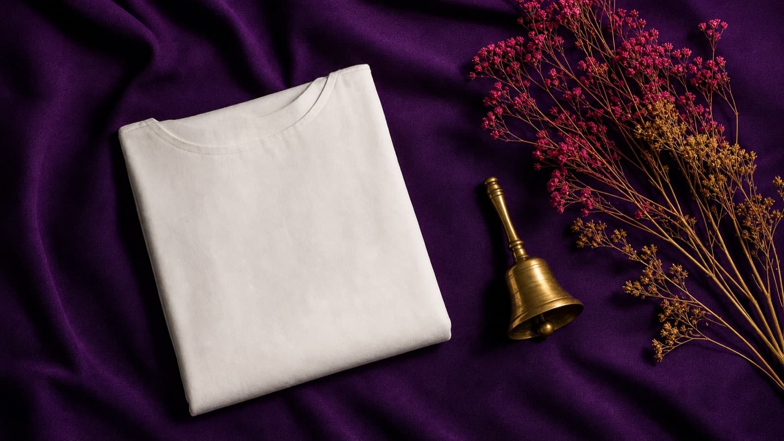 A white garment, brass bell, and flowers on purple cloth